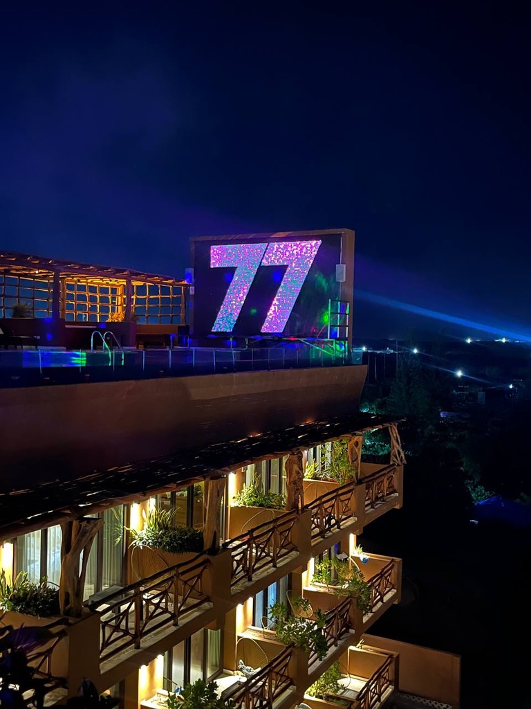The 77 screen lit up over the rooftop pool at night